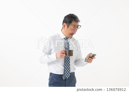 一位面帶微笑的商人,手裡拿著一杯咖啡 一位面帶微笑的商人,手裡拿著一杯咖啡 136878912
