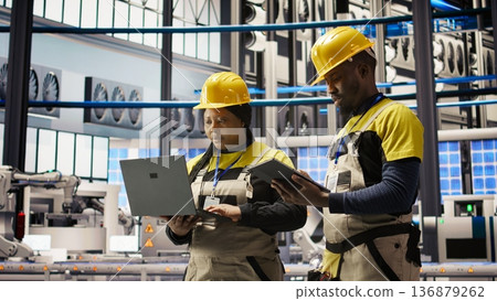 Team of smart factory mechanics working together to test systems, doing maintenance. Industry 4.0 plant teamworking repairmen inspecting equipment to identify glitches, doing brainstorming, camera A Team of smart factory mechanics working together to test systems, doing maintenance. Industry 4.0 plant teamworking repairmen inspecting equipment to identify glitches, doing brainstorming, camera A 136879262