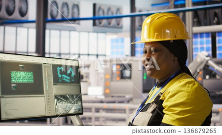 Happy engineer in smart photovoltaics factory looking at system performance metrics. Smiling worker in solar panels plant tracking energy production through IoT sensors, camera A Happy engineer in smart photovoltaics factory looking at system performance metrics. Smiling worker in solar panels plant tracking energy production through IoT sensors, camera A 136879265