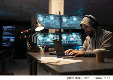 Adult male developer focusing intensely on encrypted network activity. Cybersecurity specialist types new software lines, detects threats and strengthens system defenses through diligent monitoring. Adult male developer focusing intensely on encrypted network activity. Cybersecurity specialist types new software lines, detects threats and strengthens system defenses through diligent monitoring. 136879334
