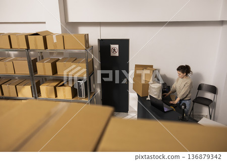 Team of dispatch workers managing shipment quality control, managing packages and supporting e-business in house operations with accurate delivery logistics. Product handling in small depot. Team of dispatch workers managing shipment quality control, managing packages and supporting e-business in house operations with accurate delivery logistics. Product handling in small depot. 136879342