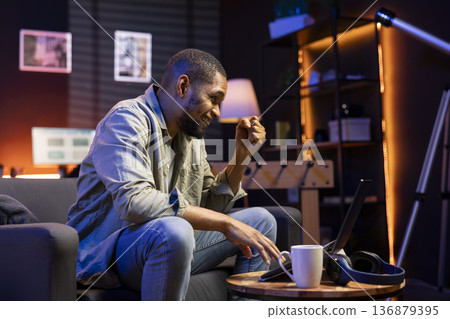 African american self employed guy celebrating his achievement at home, feeling pleased with his career success and progress. Young adult working remotely and being proud, satisfaction. African american self employed guy celebrating his achievement at home, feeling pleased with his career success and progress. Young adult working remotely and being proud, satisfaction. 136879395