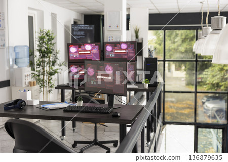 Desktop monitors show system error warnings in empty office workspace. The scene represents software failure, technical issues and business interruption in modern IT environment. 136879635