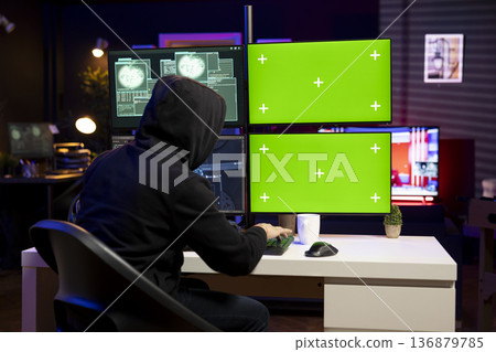 Hacker using malicious virus on green screen mockup PC to compromise devices and digital networks, gaining passwords. Man using chroma key isolated screen computer to steal and sell data online 136879785
