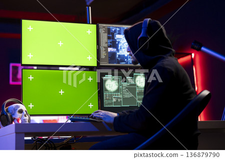 Hacker listening music doing covert operations, using green screen PC to bypass security. Rogue engineer wearing headphones engineering data theft script to penetrate firewalls using mockup computer Hacker listening music doing covert operations, using green screen PC to bypass security. Rogue engineer wearing headphones engineering data theft script to penetrate firewalls using mockup computer 136879790