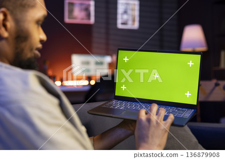 Confident male freelancer utilizing isolated copy space in the living room, laying on his sofa in a modern living room decorated with neon lights and trendy furniture. Guy with gadgets. Confident male freelancer utilizing isolated copy space in the living room, laying on his sofa in a modern living room decorated with neon lights and trendy furniture. Guy with gadgets. 136879908