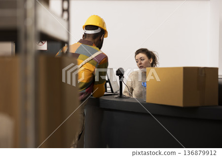 Small business staff members organizing shipments and checking stock before shipment, managing inventory and packaging for drop shipping. Employees in e-shop small scale warehouse. Small business staff members organizing shipments and checking stock before shipment, managing inventory and packaging for drop shipping. Employees in e-shop small scale warehouse. 136879912