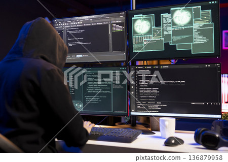 Cybercriminal coding on PC, creating stealth malware that evades security software. Hacker using programming language on computer to make script hiding malicious code from detection systems 136879958