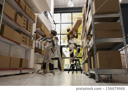 Female worker scanning airway bills labels and listening to music on headset, verifying goods on shelving units to ensure accurate shipment service. Quality control and efficient logistics. Female worker scanning airway bills labels and listening to music on headset, verifying goods on shelving units to ensure accurate shipment service. Quality control and efficient logistics. 136879988