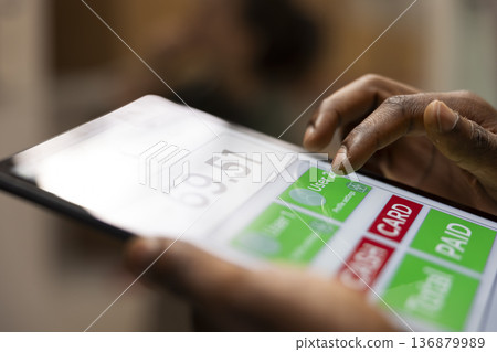 Close up of small business staff member checking inventory for dispatch, ensuring storage and shipment of goods runs smoothly in support of e-business logistics and express delivery. Close up of small business staff member checking inventory for dispatch, ensuring storage and shipment of goods runs smoothly in support of e-business logistics and express delivery. 136879989