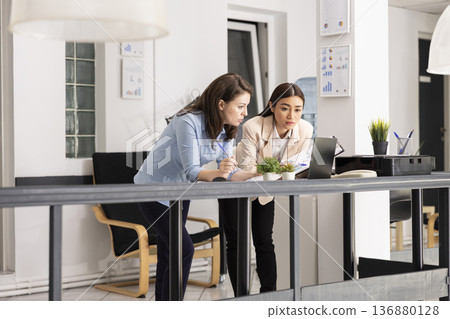 Businesswomen analyzing information on laptop and planning upcoming projects. Female marketing team reviews financial strategy using data reports and digital dashboards to guide company decisions. Businesswomen analyzing information on laptop and planning upcoming projects. Female marketing team reviews financial strategy using data reports and digital dashboards to guide company decisions. 136880128