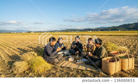 A group of young farmers eating rice balls in a rice field after harvest 136880653