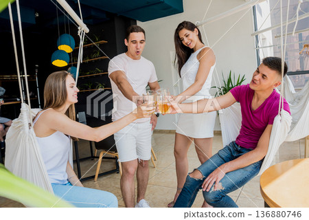 Cheerful friends in the pub. Drinking beer, talking, having fun. Cheerful friends in the pub. Drinking beer, talking, having fun. 136880746