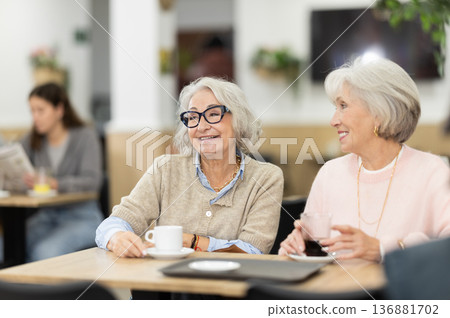 Elderly women sitting in a coffee shop and chatting Elderly women sitting in a coffee shop and chatting 136881702