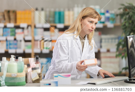 Female pharmacist looking for pills on computer Female pharmacist looking for pills on computer 136881703