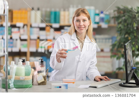 Female pharmacist working at computer and holding package of pills Female pharmacist working at computer and holding package of pills 136881704