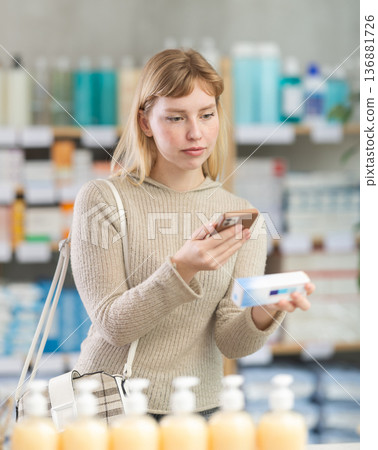 woman scans a package of ointment on her phone 136881726