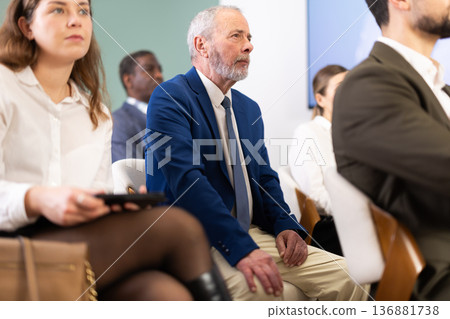 Eldery man listens to presentation in conference room Eldery man listens to presentation in conference room 136881738