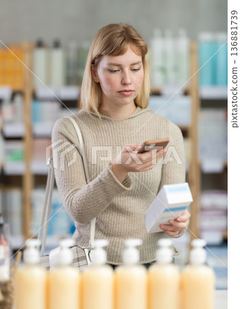 Girl in autumn clothes scans code on cough syrup to check expiration date Girl in autumn clothes scans code on cough syrup to check expiration date 136881739