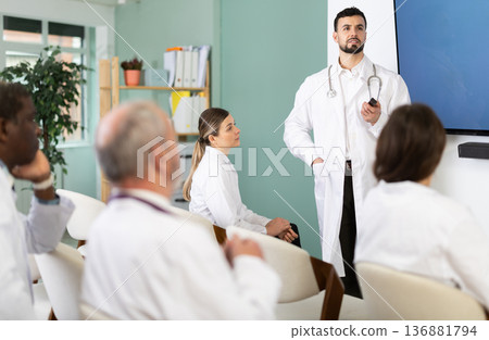Male doctor holds a remote control rod in his hands and gives a lecture Male doctor holds a remote control rod in his hands and gives a lecture 136881794