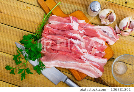 Fresh pork bacon with garlic, pepper on wooden table in kitchen 136881801