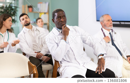 African man doctor student at courses meeting listens to teacher and look at speaker African man doctor student at courses meeting listens to teacher and look at speaker 136881806
