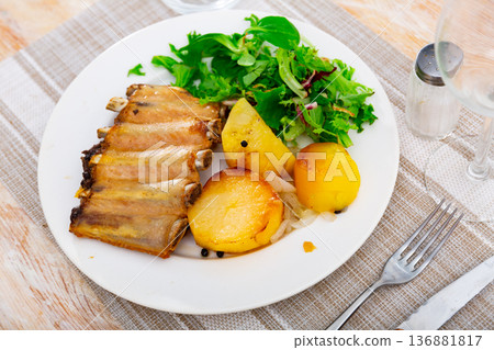 Pork ribs with boiled potatoes and fresh salad leaves 136881817