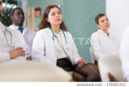 Girl doctor student at courses meeting listens to teacher and look at speaker Girl doctor student at courses meeting listens to teacher and look at speaker 136881822