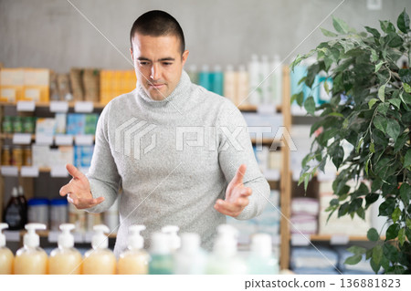 Portrait of man in winter clothes shopper choosing some products in supermarket Portrait of man in winter clothes shopper choosing some products in supermarket 136881823