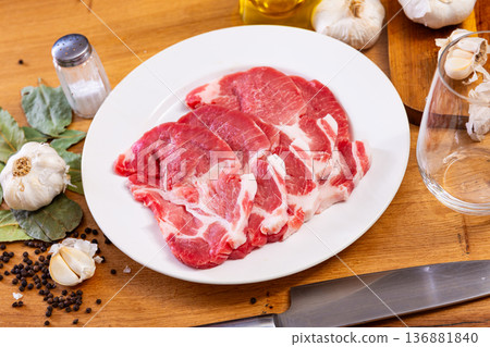 Raw pork neck on the kitchen table along with other ingredients for making delicious lunch or dinner 136881840
