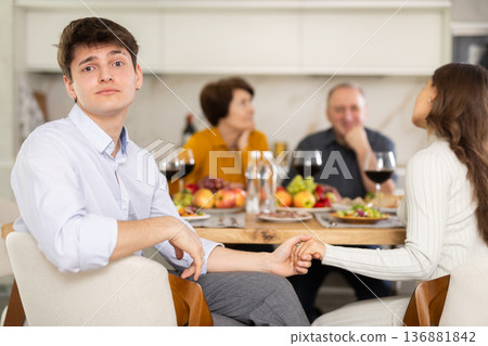 Shocked guy sitting at family dinner with comforting girlfriend Shocked guy sitting at family dinner with comforting girlfriend 136881842