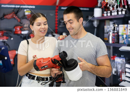 Couple talking while choosing paint sprayer in hardware store Couple talking while choosing paint sprayer in hardware store 136881849
