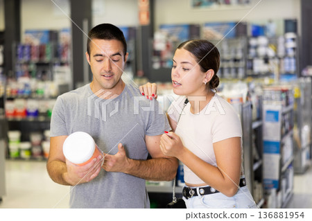 Positive young couple talking and looking for paints in store Positive young couple talking and looking for paints in store 136881954