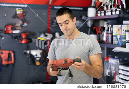 Focused man choosing electric drill in local hardware store 136881976