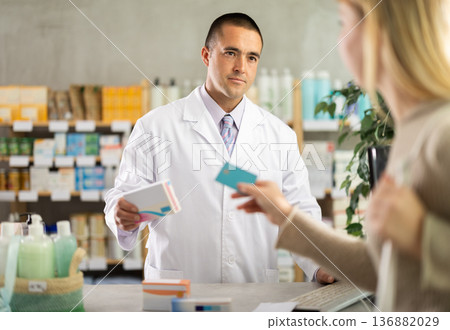 male pharmacist communicates with a client on card payment male pharmacist communicates with a client on card payment 136882029