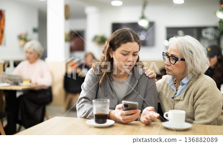 Grandmother comforts her upset daughter while having lunch at cafe 136882089