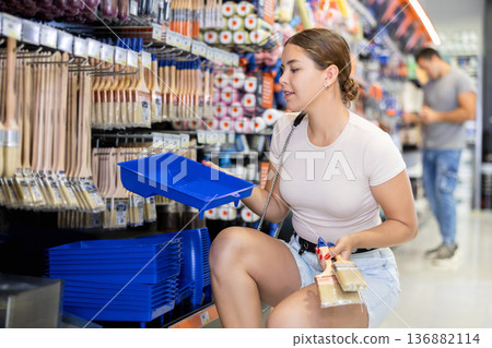 Woman buy brushes and tray expendable materials in paint department of construction store. Woman buy brushes and tray expendable materials in paint department of construction store. 136882114