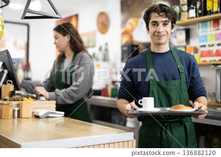 Barista guy presenting coffee and croissant, give out order Barista guy presenting coffee and croissant, give out order 136882120