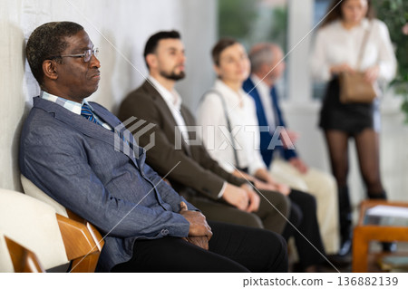 Applicants are waiting for interview, there is queue of people sitting in waiting room. Applicants are waiting for interview, there is queue of people sitting in waiting room. 136882139