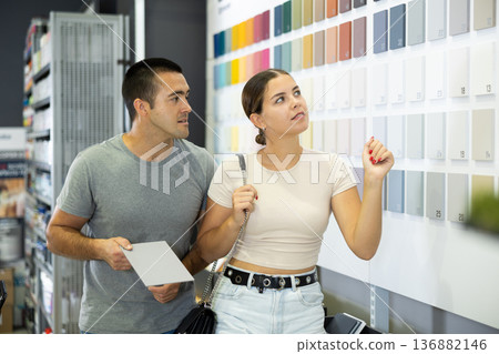 Couple choosing paint colors on swatch stand in construction hypermarket Couple choosing paint colors on swatch stand in construction hypermarket 136882146