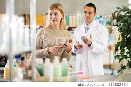Woman with mobile phone on pharmacist background Woman with mobile phone on pharmacist background 136882384