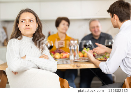 Upset young woman feeling distanced at family meal Upset young woman feeling distanced at family meal 136882385