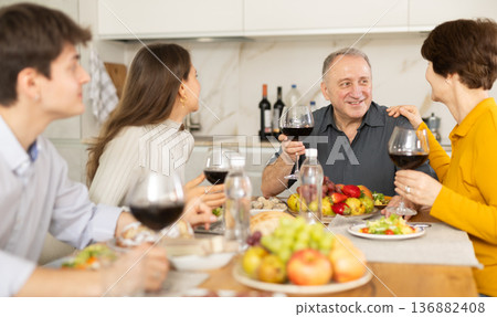 Father and mother together with adult children talking at dinner table at home Father and mother together with adult children talking at dinner table at home 136882408