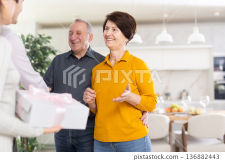 Smiling elderly parents welcoming daughter with husband at home Smiling elderly parents welcoming daughter with husband at home 136882443