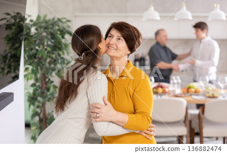 Happy mother meets her daughter, hugs and kisses her. In the background father shakes guy hand 136882474