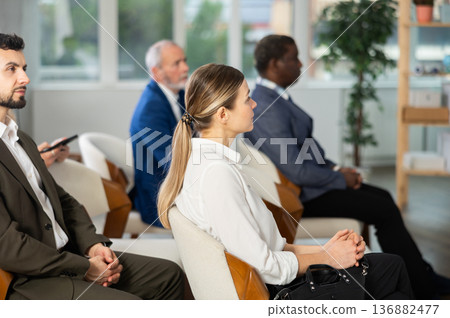 Adult woman listens to presentation in conference room 136882477