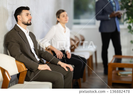 Applicants are waiting for interview, there is queue of people sitting in waiting room. 136882478