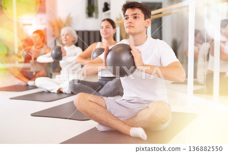 Men and women doing pilates exercises with fitness ball at gym Men and women doing pilates exercises with fitness ball at gym 136882550