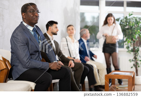 Applicants are waiting for interview, there is queue of people sitting in waiting room. Applicants are waiting for interview, there is queue of people sitting in waiting room. 136882559