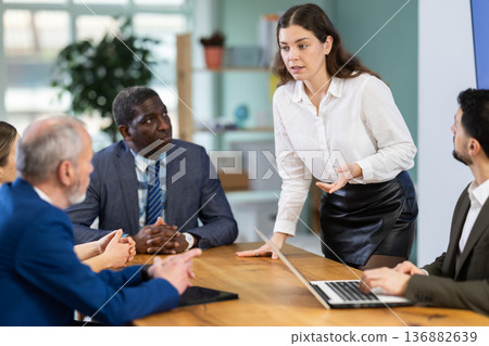Girl stands in front of business colleagues, tells report Girl stands in front of business colleagues, tells report 136882639
